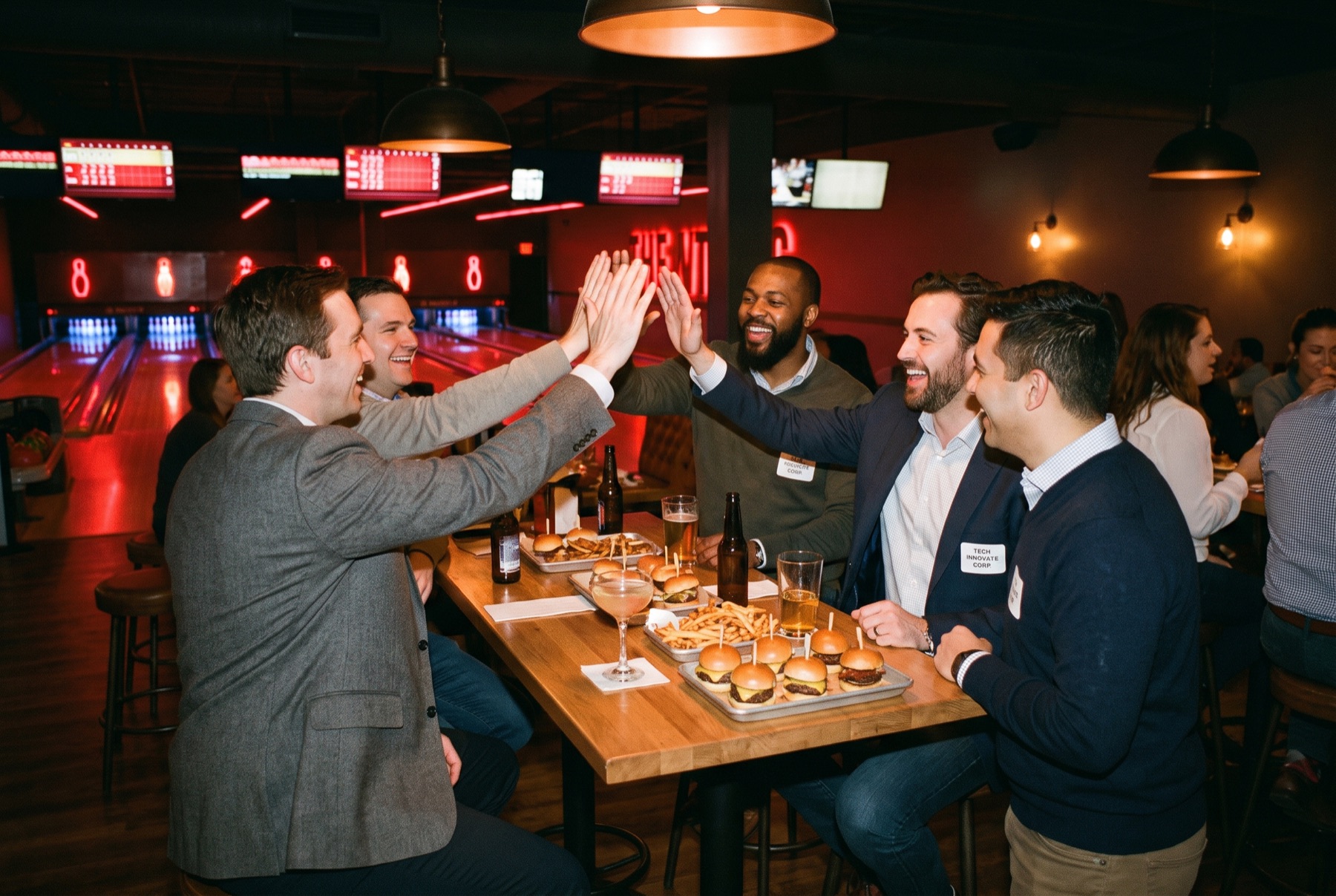 Colleagues high-fiving at a team bowling night